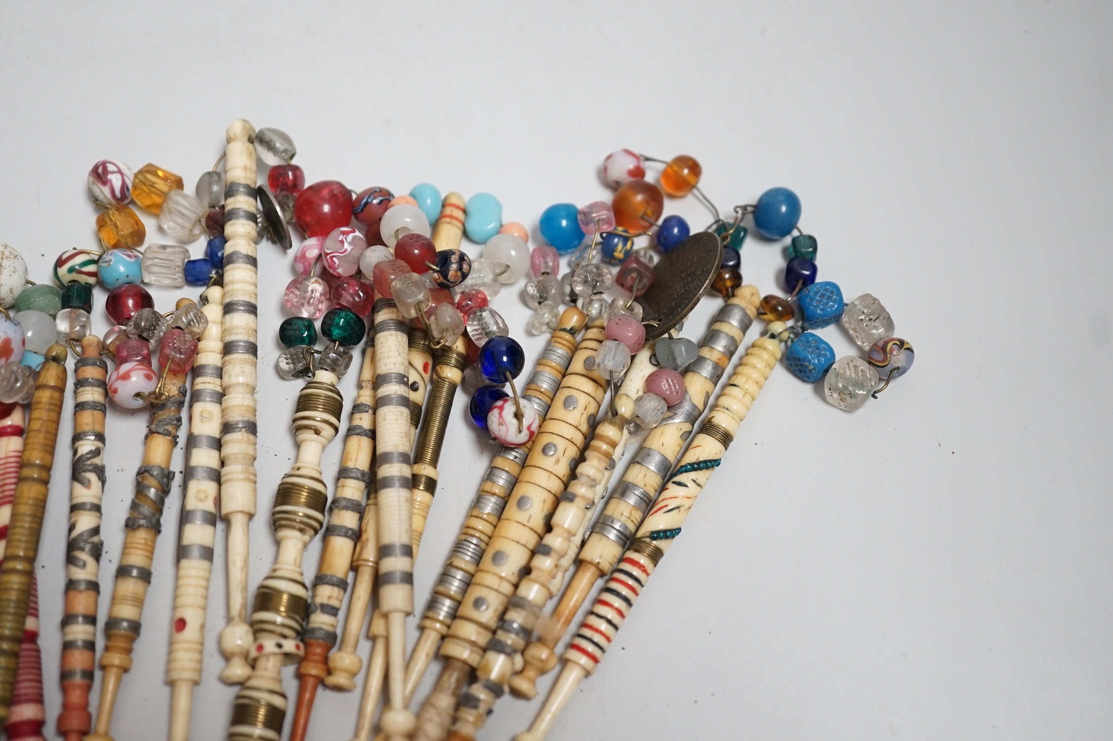 Twenty one 19th century stained and turned bone lace bobbins with glass bead tops and thirteen ornate bone and metal decorated lace bobbins with bead tops (35)